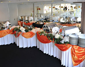 Reception food station with tables draped with orange fabric